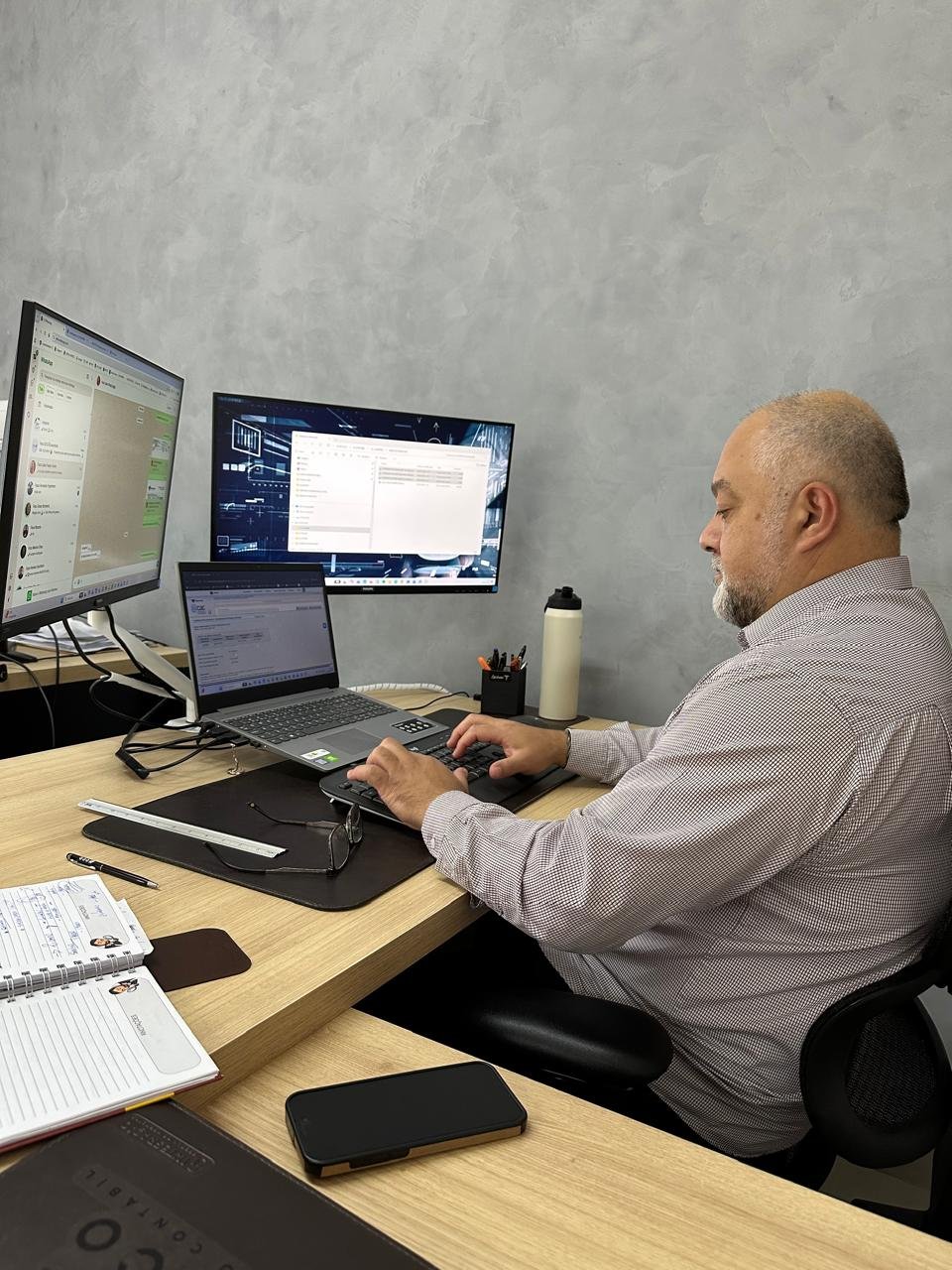 Luciano trabalhando no computador, analisando os números de um cliente